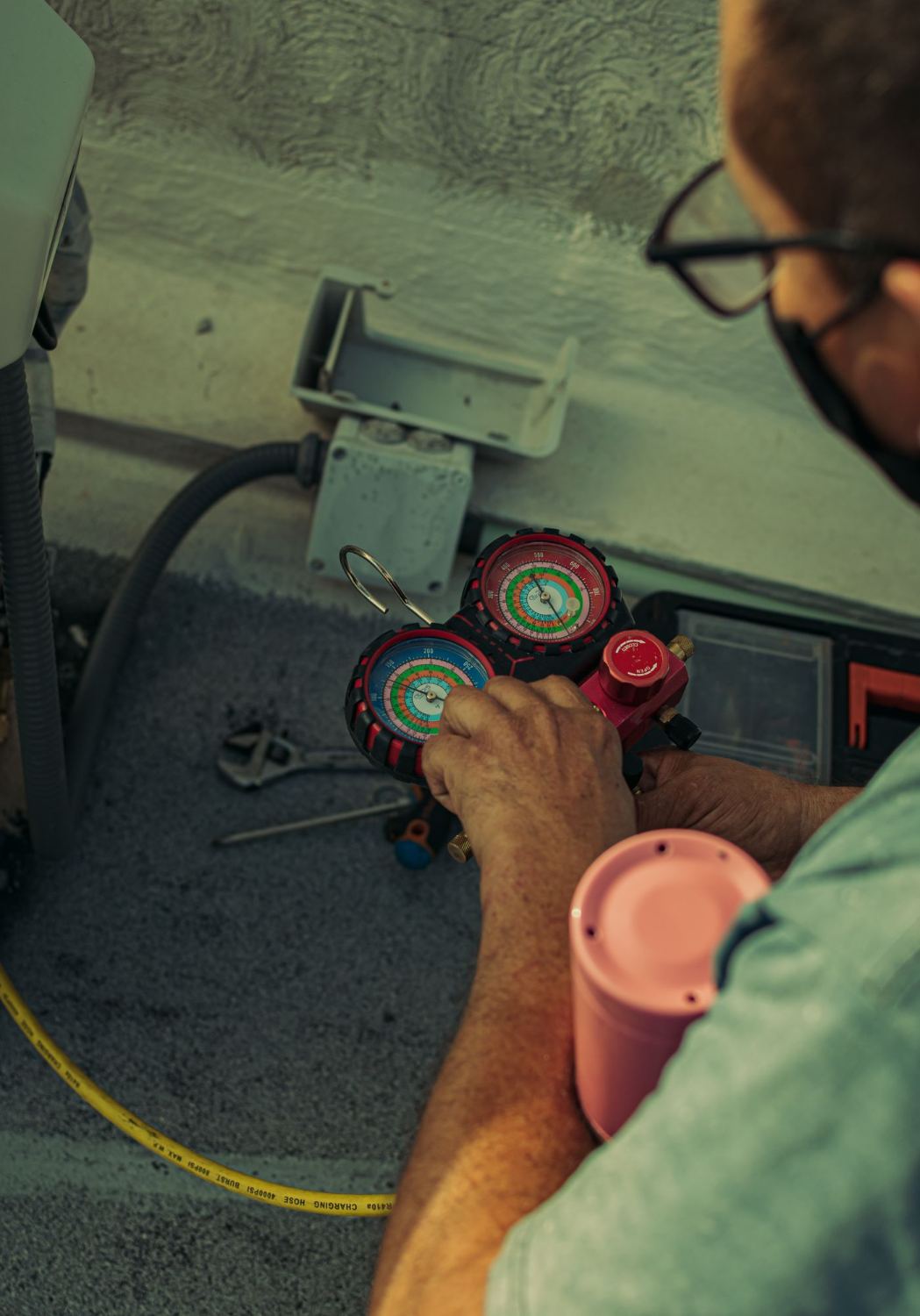 Technician reading refrigerant pressure gauges during an AC service