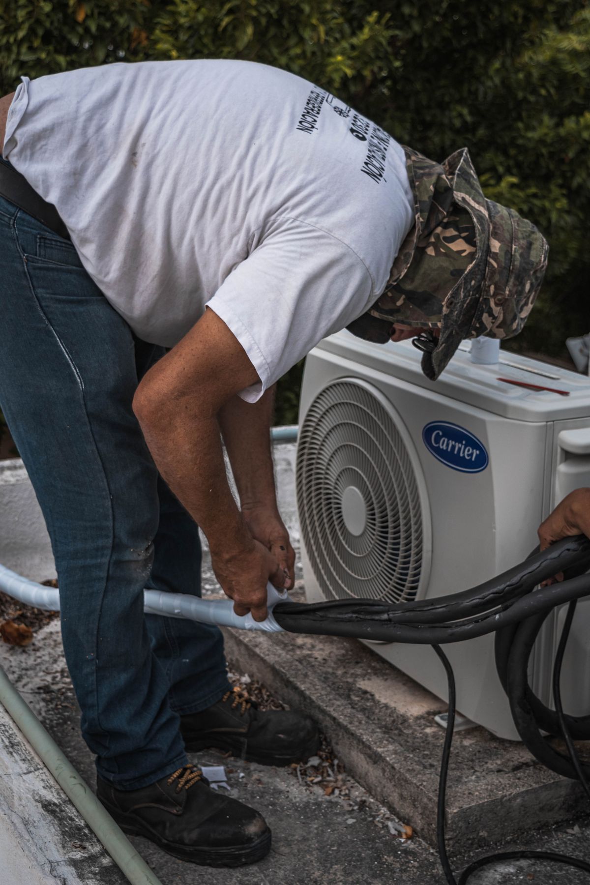 Technician connecting service hoses to an outdoor AC unit